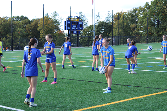 Varsity girls soccer team warms up on the upper field awaiting the completion of the football game