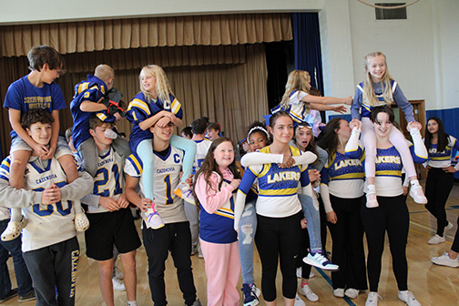 Varsity student athletes prop up 4th grade students on their shoulders