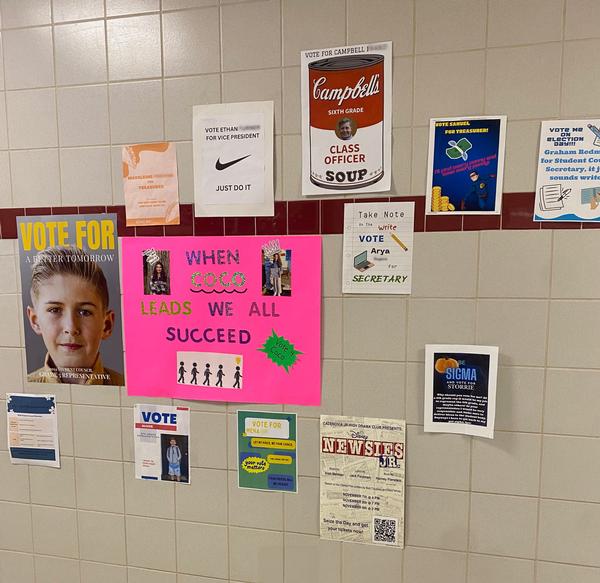 The middle school wall is posted with various posters for students running in the campaign.